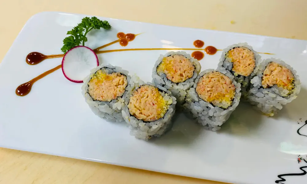 Spicy crab sushi roll radish garnish dark soy sauce drizzle white plate at Osaka Hibachi & Sushi, a Japanese Restaurant in Bainbridge